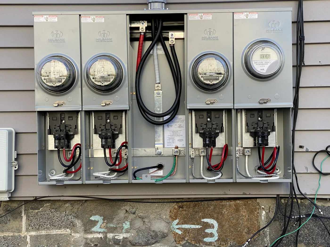 Bank of electrical meters and service disconnects installed on the exterior of a multi-unit building