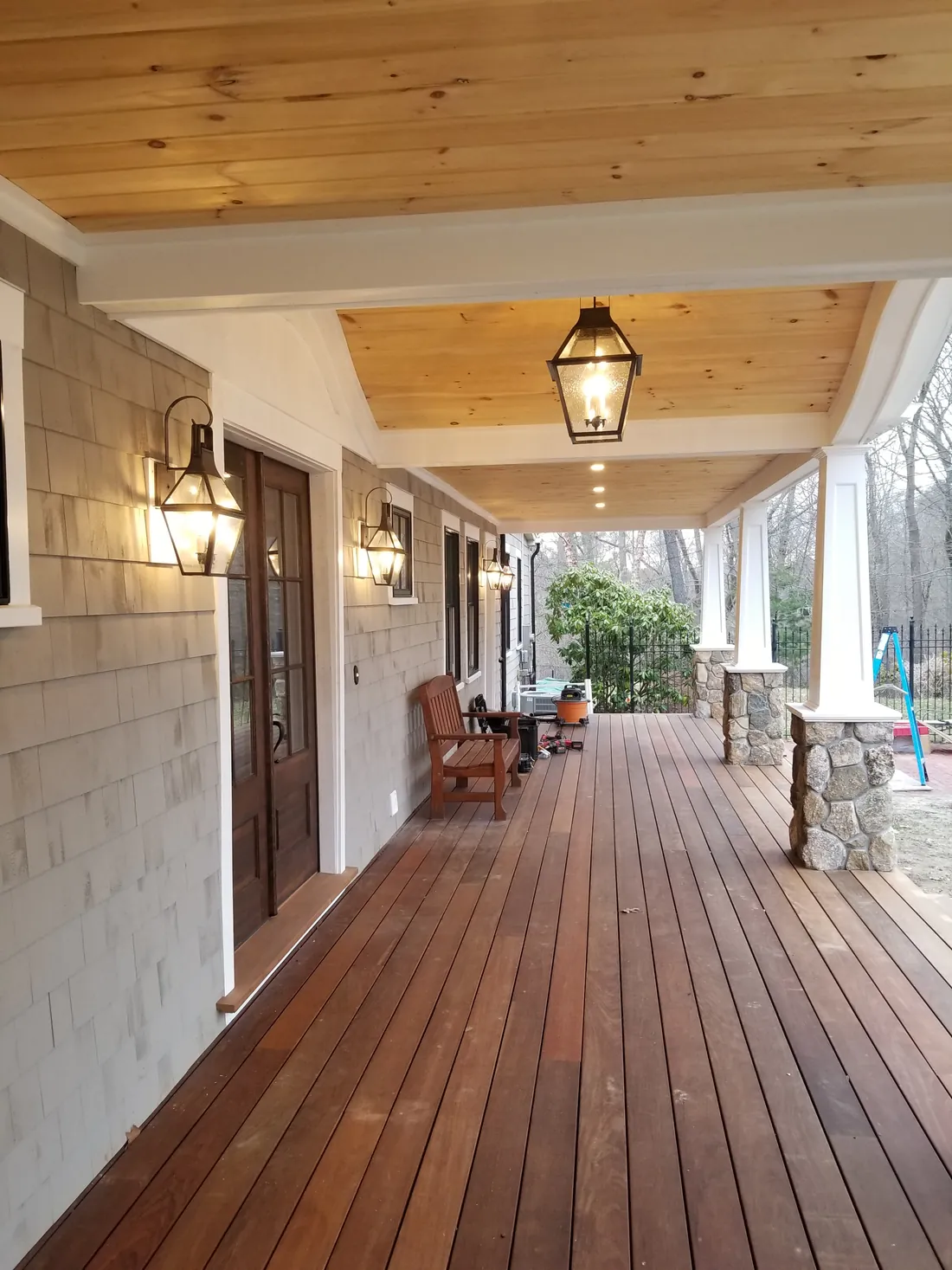 Covered porch lit by lantern wall sconces, a hanging lantern and recessed ceiling lights